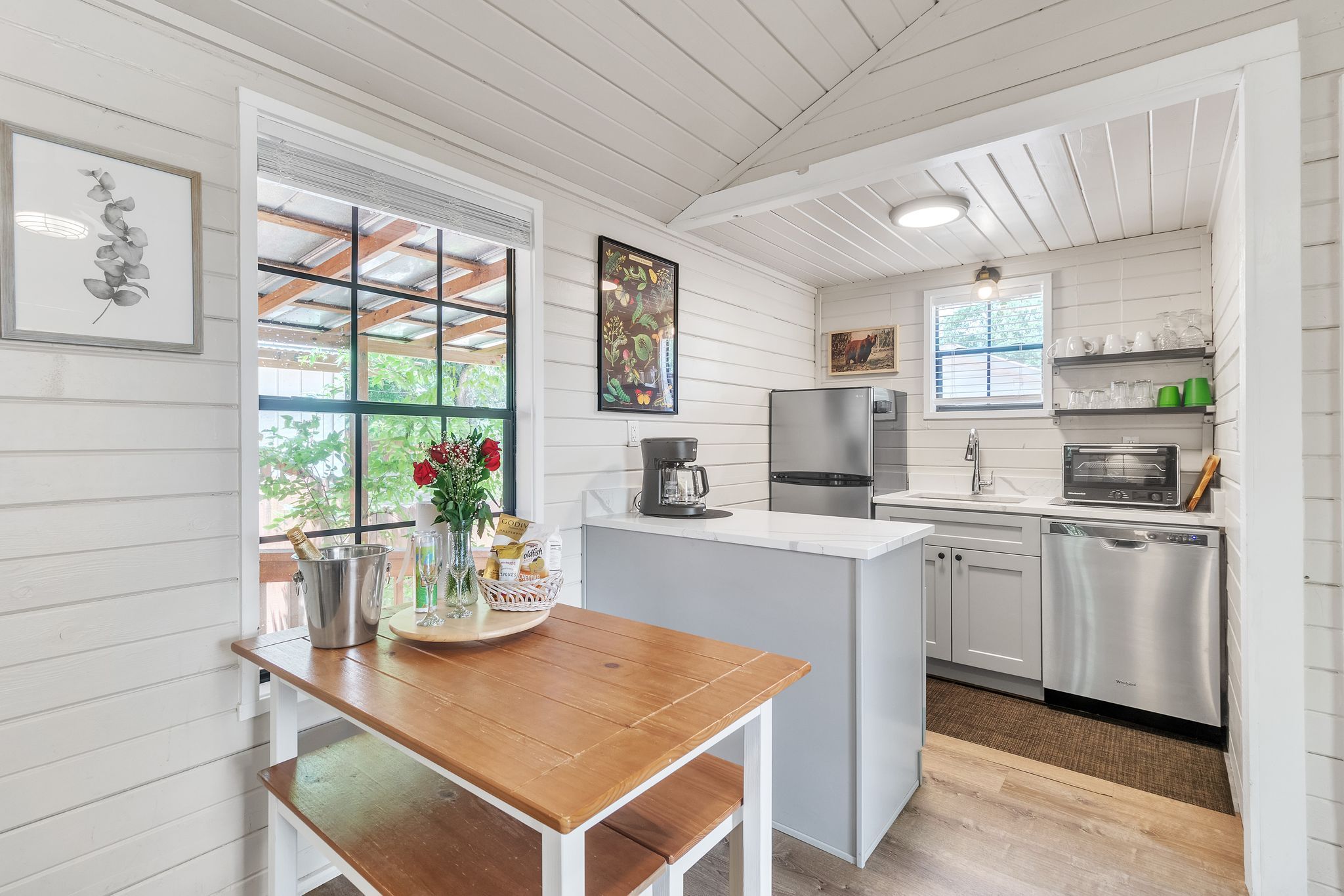 A kitchen with white cabinetry, a wooden table, and a refrigerator.