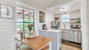 A kitchen with white cabinetry, a wooden table, and a refrigerator.