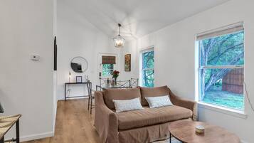 A modern living room with a brown sofa, a round coffee table, and a dining area with a table and chairs.