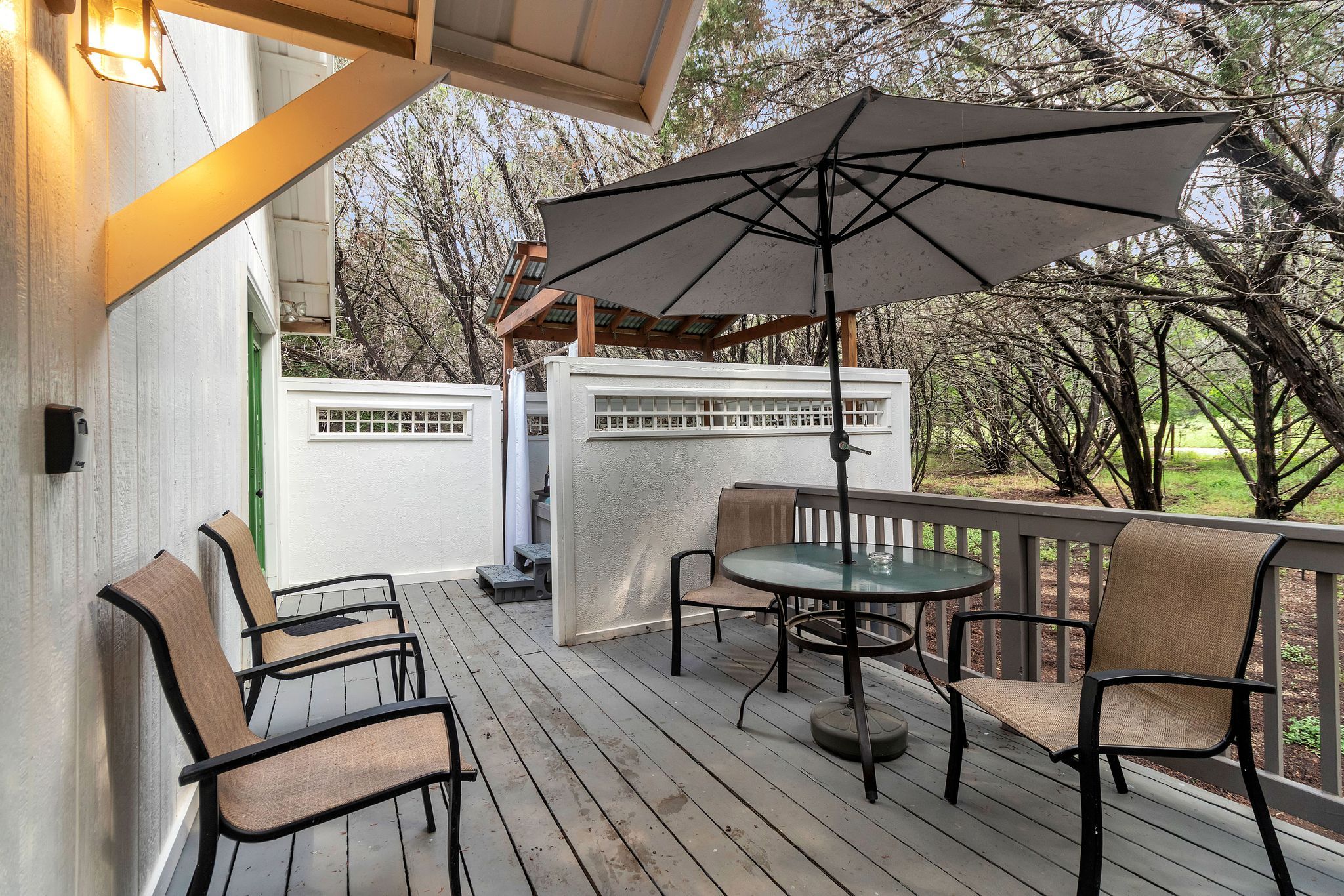A wooden deck with outdoor furniture, including chairs and a table, under a large umbrella.