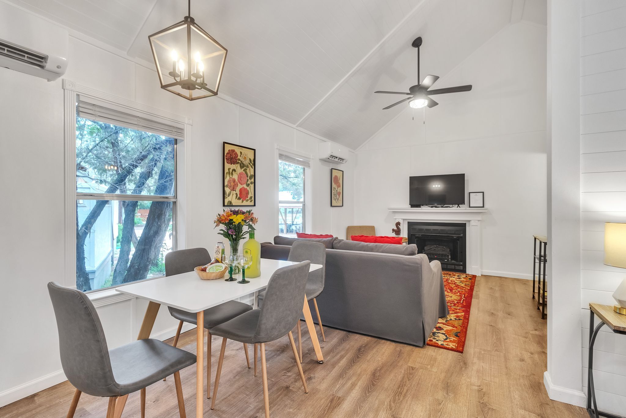 A modern living room with a fireplace, a television, and a dining area with a table and chairs.