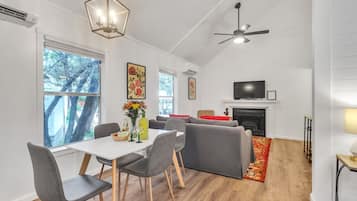 A modern living room with a fireplace, a television, and a dining area with a table and chairs.