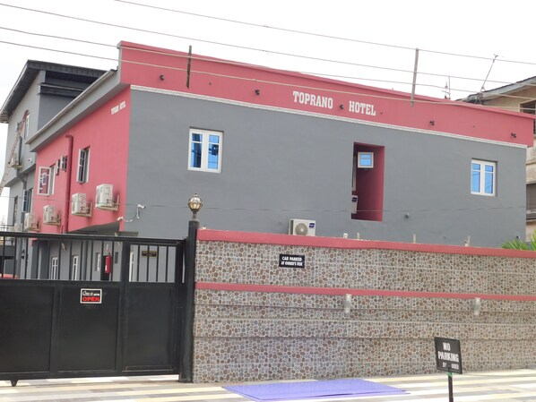 A building with a red and grey facade, labeled "Toprano Hotel." - Toprano Hotel (Lagos)