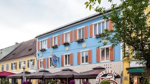 A row of colorful buildings with outdoor seating and flower pots. - Hotel Restaurant Kollar Göbl (Deutschlandsberg)