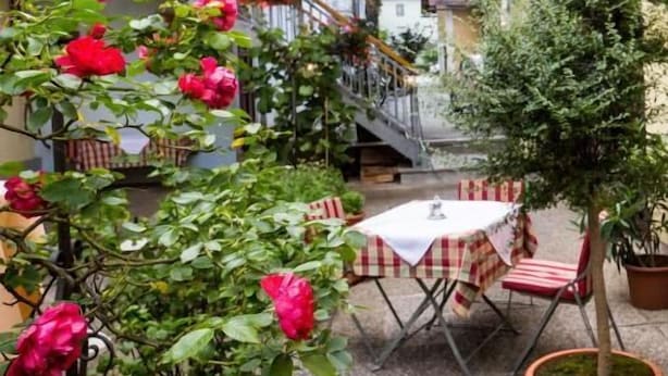 A courtyard with a table and chairs, a staircase, and a potted tree. - Hotel Restaurant Kollar Göbl (Deutschlandsberg)