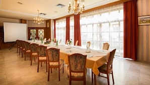 A conference room with a long table, chairs, a projector screen, and large windows with curtains. - Hotel Restaurant Kollar Göbl (Deutschlandsberg)