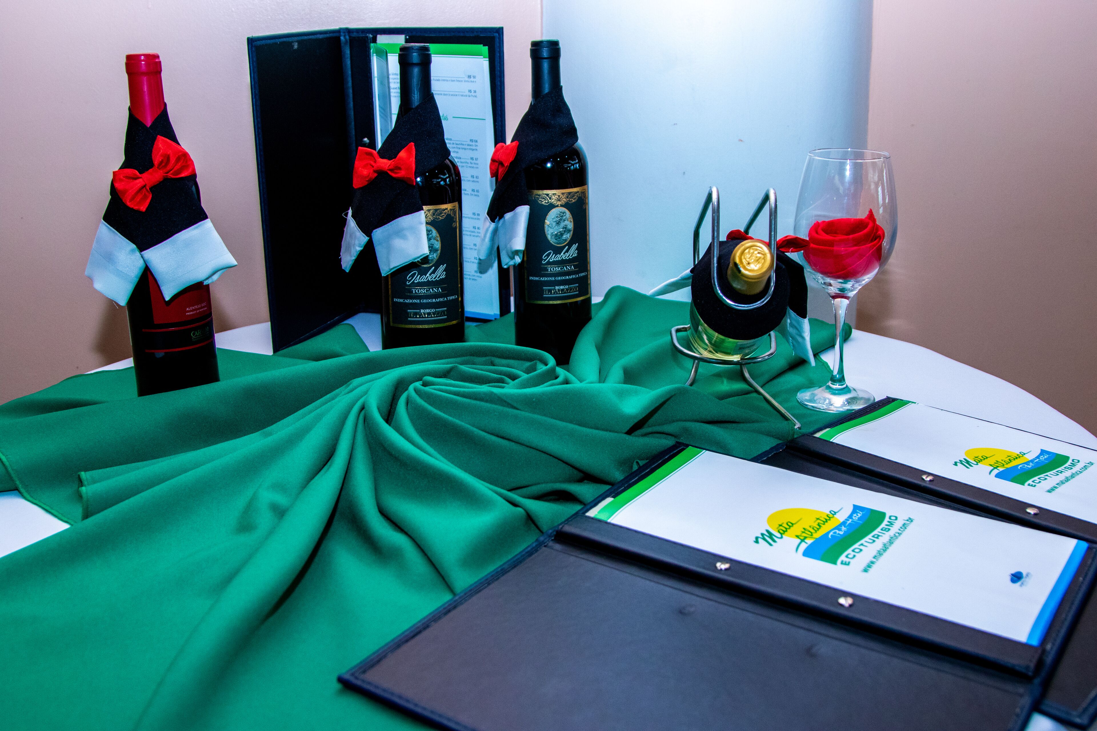 A table with wine bottles, a glass of red wine, and a menu.