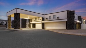 Un edificio moderno con entrada cubierta, grandes puertas de garaje y pilares de piedra.