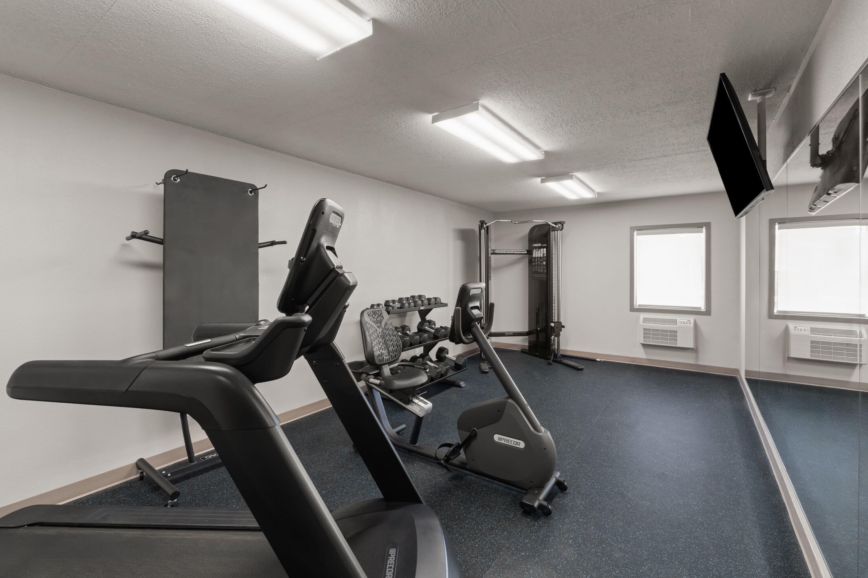 Un gimnasio con cinta de correr, elíptica y máquinas de pesas.