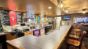 A bar area with a long counter, wooden chairs, and a menu board. - Days Inn by Wyndham Mandan Bismarck Area (Mandan)