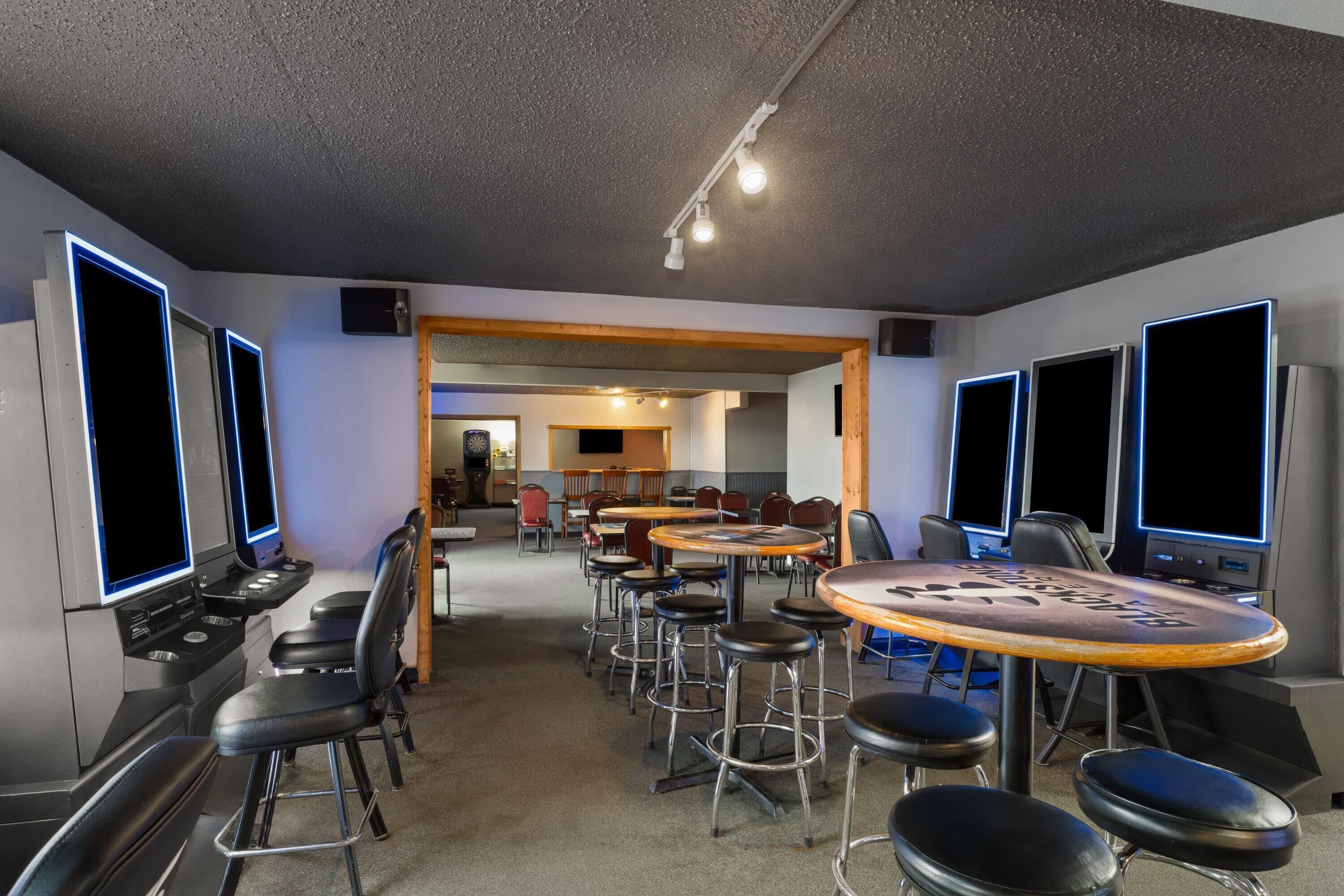 A conference room with multiple tables and chairs, a stage with a podium, and a large screen.