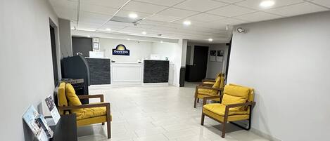 A reception area with a reception desk, a computer, and two yellow chairs.