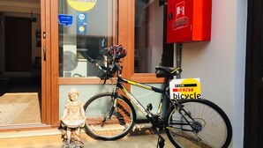 A bicycle parked outside a boutique hotel with a sign indicating it is for rent.