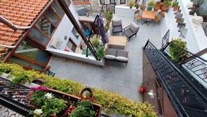 A rooftop terrace with outdoor furniture, potted plants, and a view of the surrounding buildings.