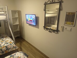 Habitación con literas y un televisor en la pared que muestra un noticiero.