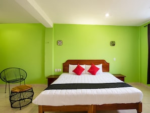 A room with a bed, a chair, and a nightstand.