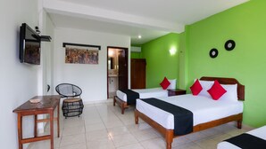 Une chambre d’hôtel avec deux lits, un bureau, une chaise et une salle de bain visible à travers une porte ouverte.