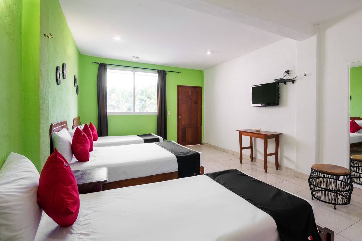 A hotel room with two beds, a TV, a small table, and a mirror.