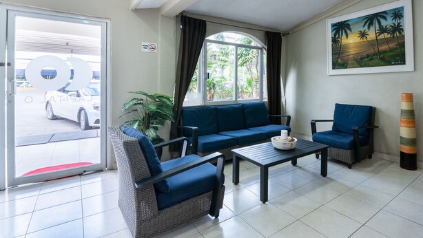 Un hall d’hôtel avec un canapé, des fauteuils, une table basse, un tableau et une vue sur l’extérieur.