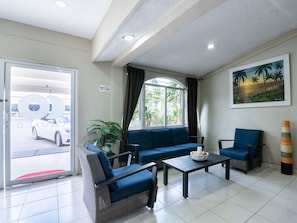 Un hall d’hôtel avec un canapé, des fauteuils, une table basse, un tableau et une vue sur l’extérieur.