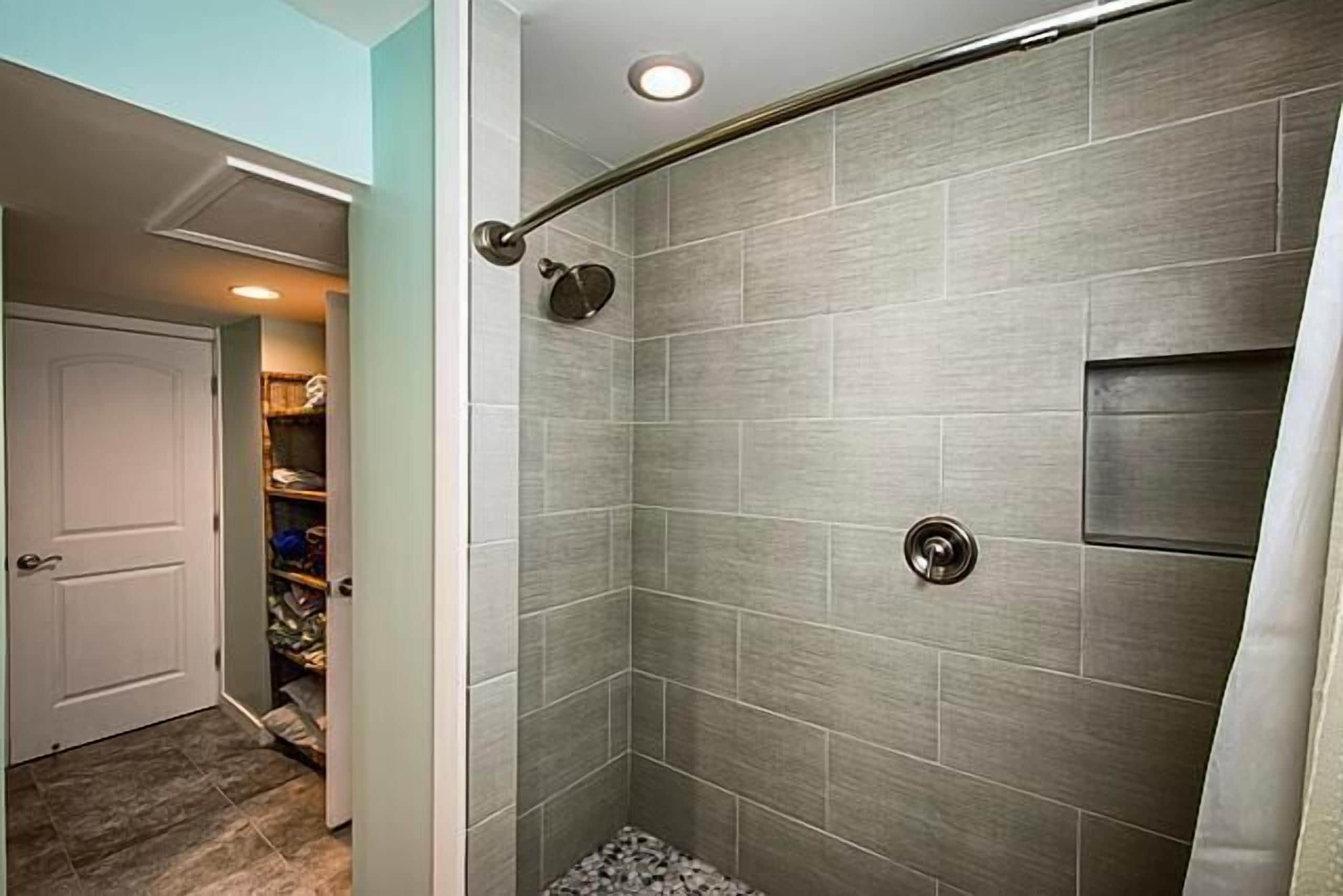 A shower with a glass door, a metal showerhead, and a tiled wall.