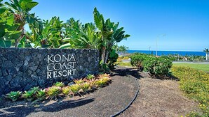 A sign for Kona Coast Resort with a pathway leading to the ocean. - Kona Coast Resort at Keauhou Gardens 8204 (Kailua-Kona)