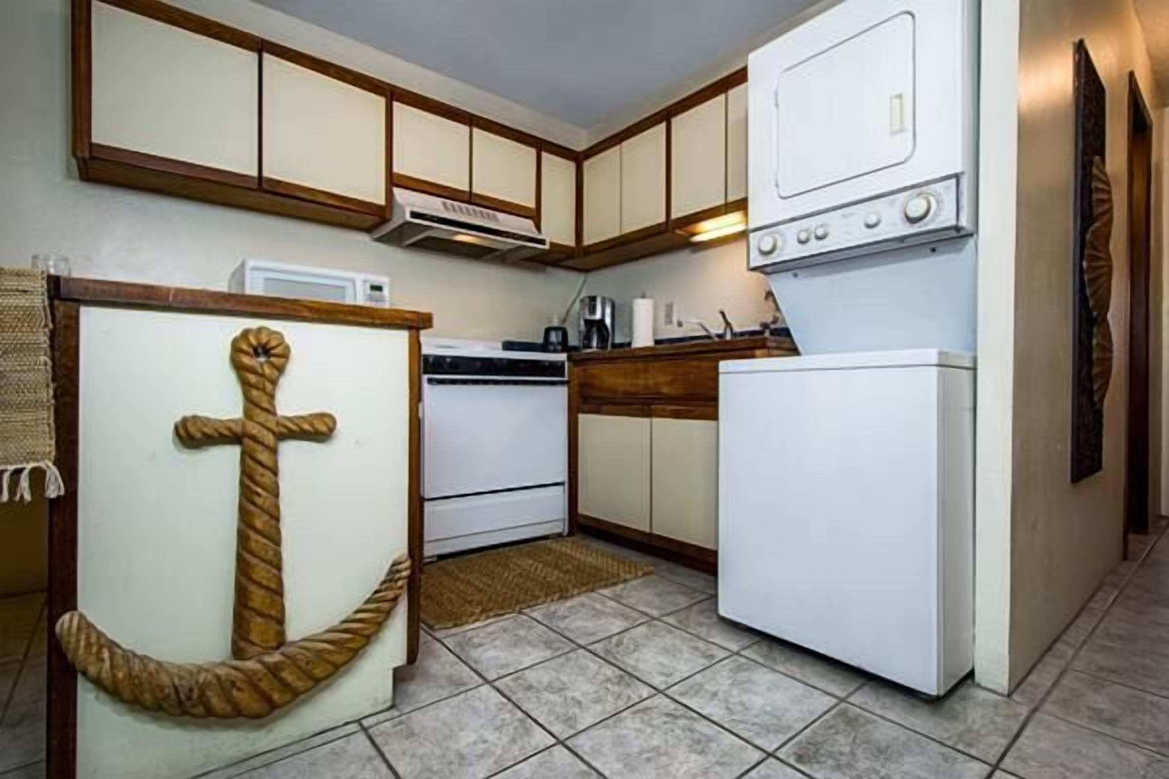 Eine kleine Küche mit Holzschränken, einem weißen Kühlschrank und einer Mikrowelle.