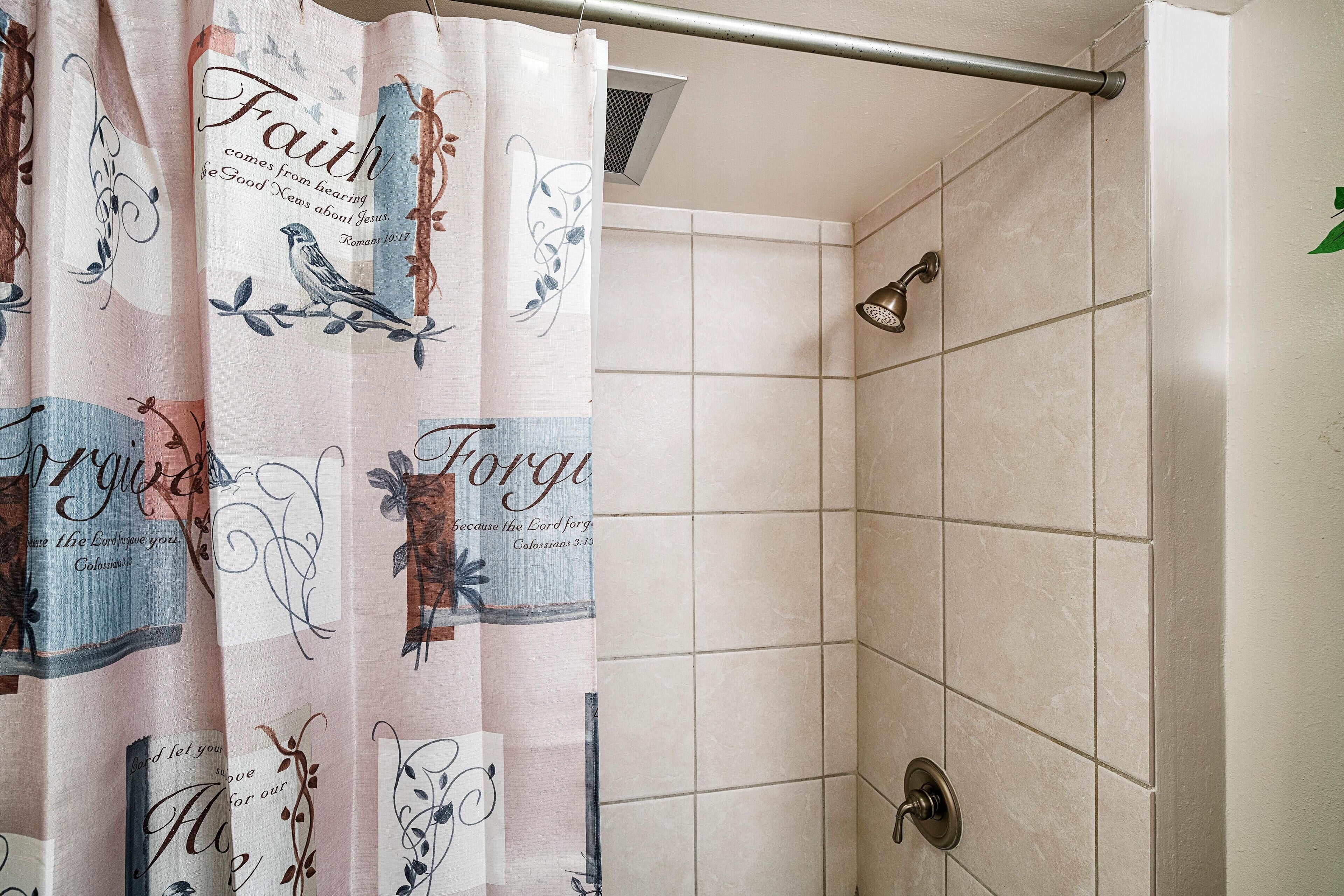 Un área de ducha con cortina decorada con motivos e inscripciones religiosas.