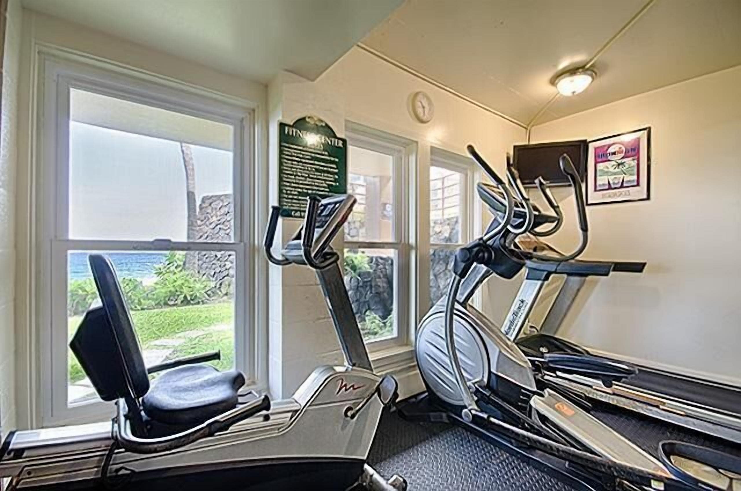 A gym with two treadmills, one elliptical, and a stationary bike.