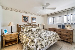 A bedroom with a bed, two nightstands, a dresser, a ceiling fan, and a window with blinds. - Casa De Emdeko 219 (Kailua-Kona)