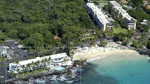 Vue aérienne d’une zone côtière avec un hôtel en bord de mer, une plage de sable et une côte rocheuse.