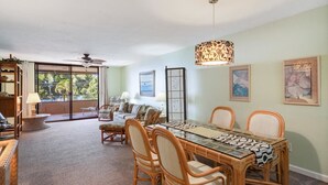 A dining area with a glass-top table, wicker chairs, and a patterned table runner.