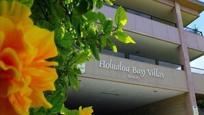A building with a sign reading "Hualoloa Bay Villas" and a phone number.
