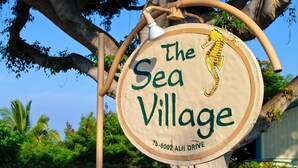 Un panneau en bois représentant un hippocampe et portant l’inscription « The Sea Village », ainsi qu’une adresse incomplète.