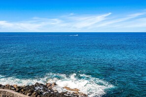A coastal view with a rocky shoreline and a clear blue sky.
