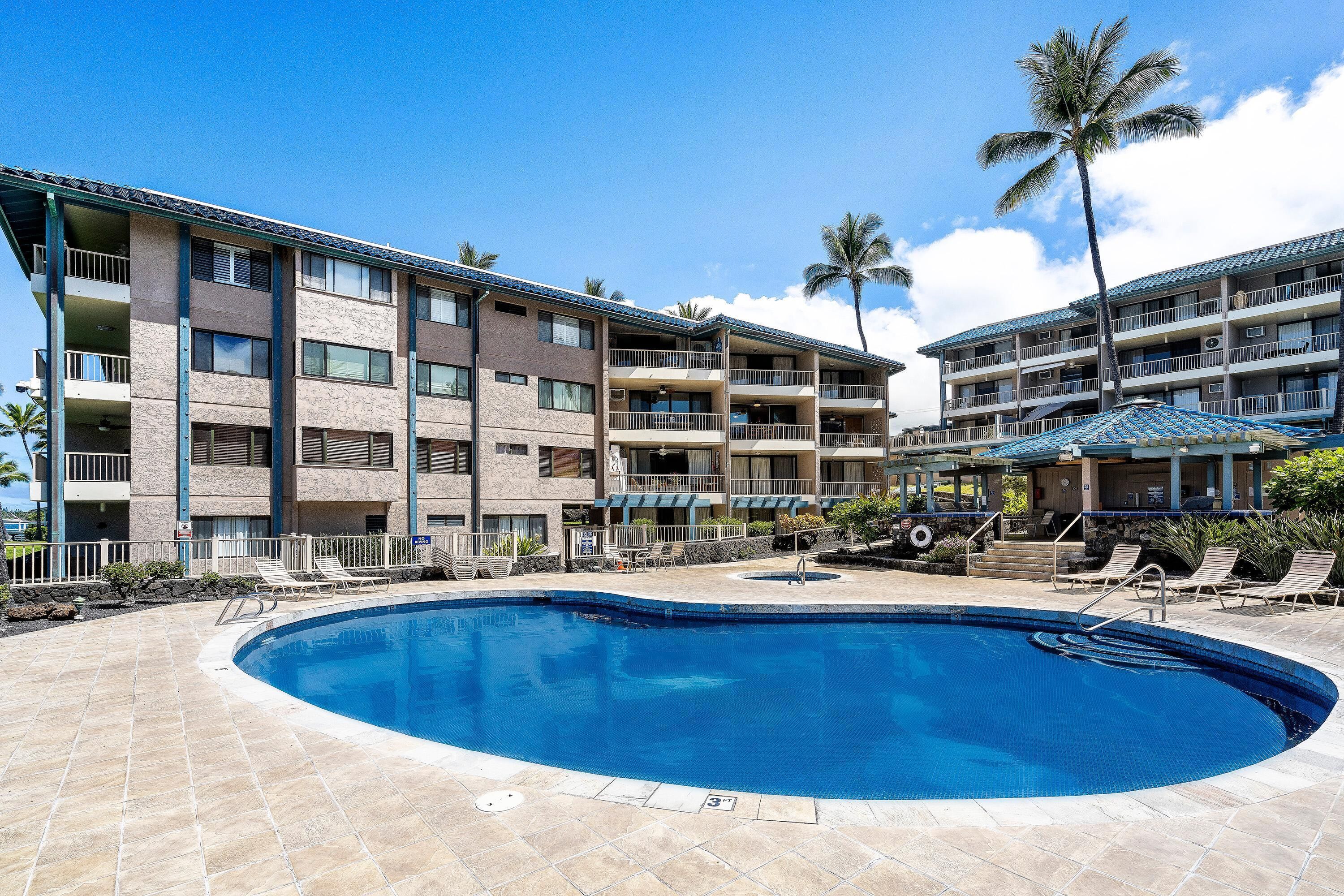 A hotel with a swimming pool, multiple balconies, and a tropical setting.