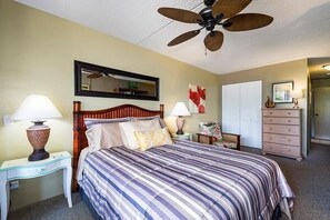 Ein Schlafzimmer mit Bett, Deckenventilator, Schminktisch und Spiegel.
