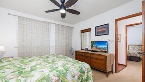 A bedroom with a bed, a dresser, a television, and a ceiling fan. - Kahaluu Bay Villas 304 (Kailua-Kona)