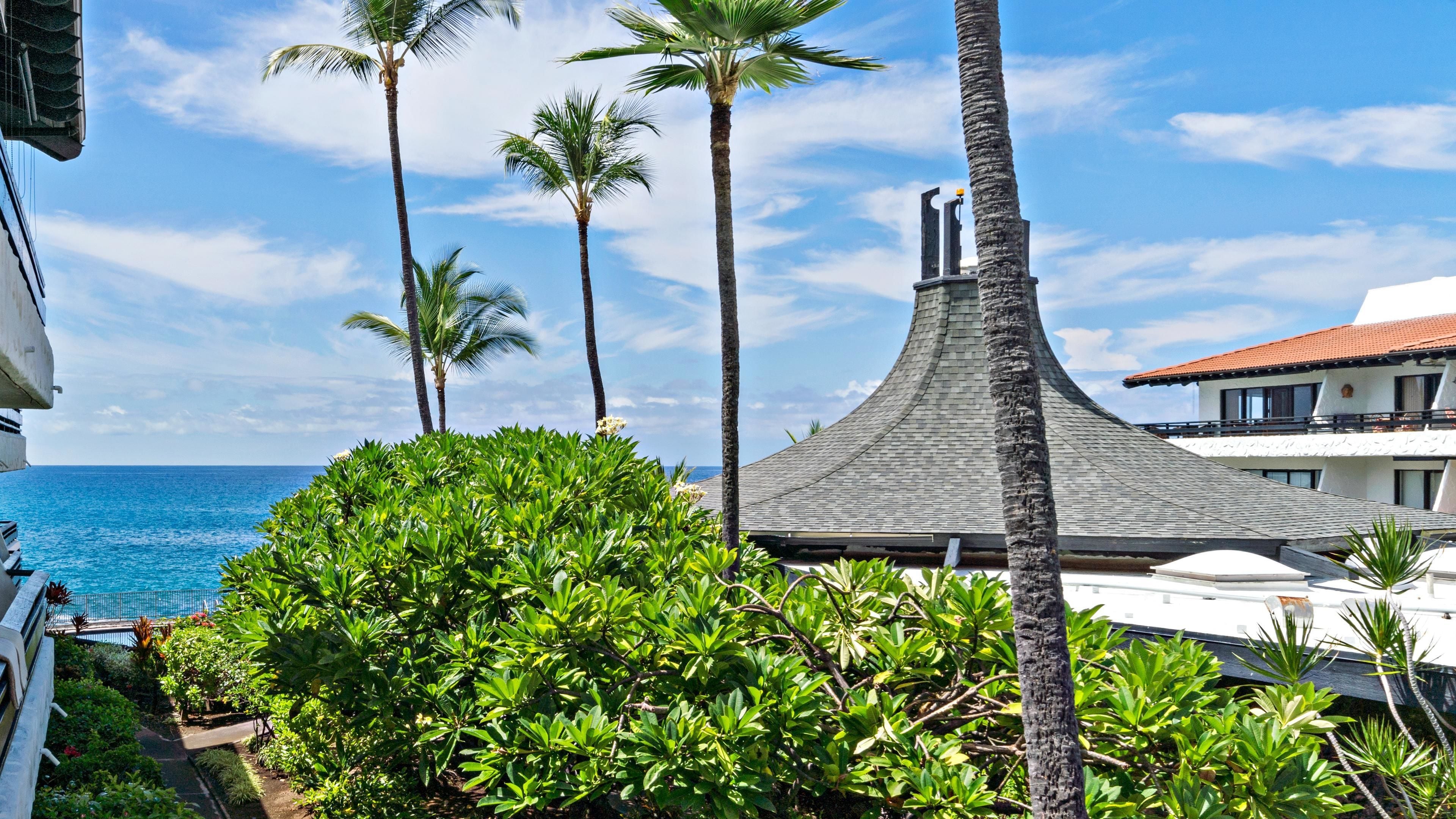 A beachfront property with a pool, palm trees, and a distinctive building with a conical roof.