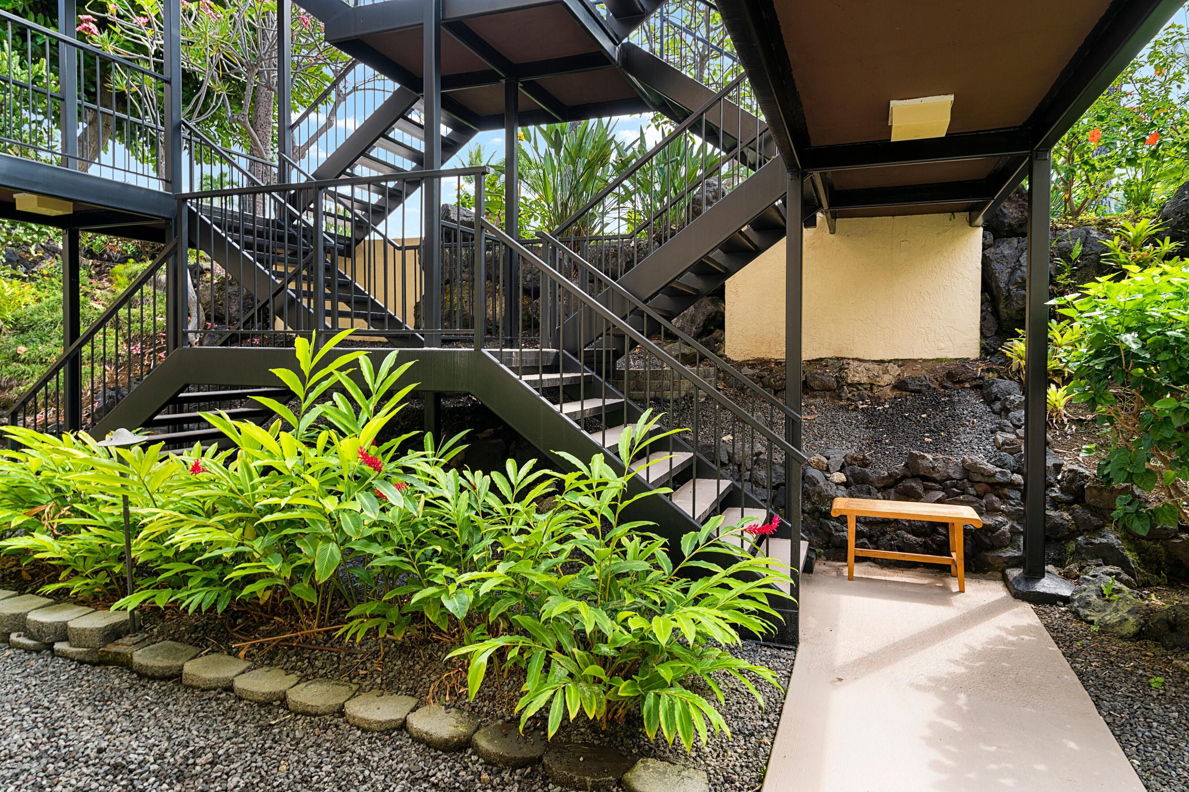 A staircase with metal railings leading to a covered area with a bench.