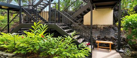 A staircase with metal railings leading to a covered area with a bench.