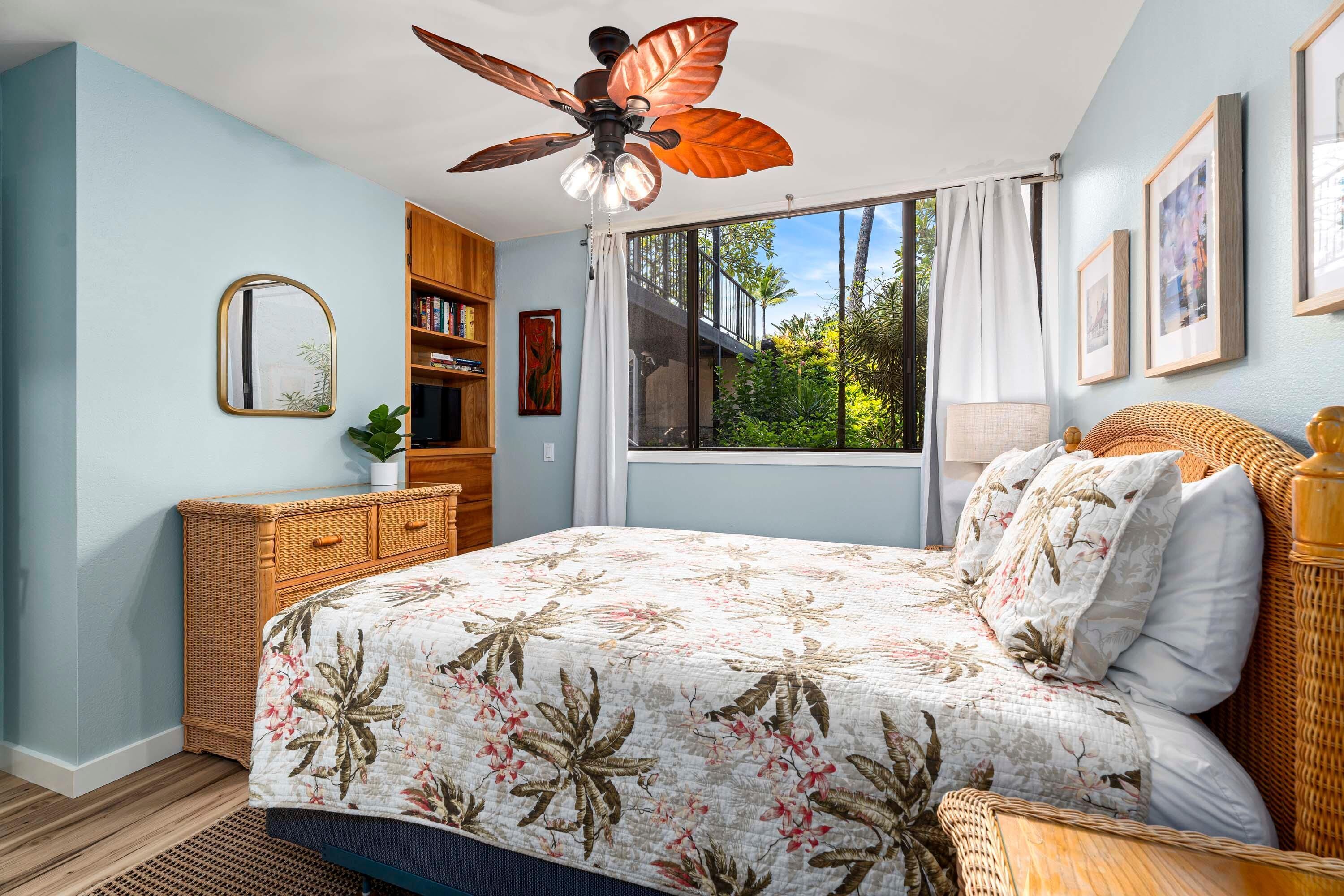 A bedroom with a bed, a ceiling fan, a window with curtains, a bookshelf, and a framed picture on the wall.