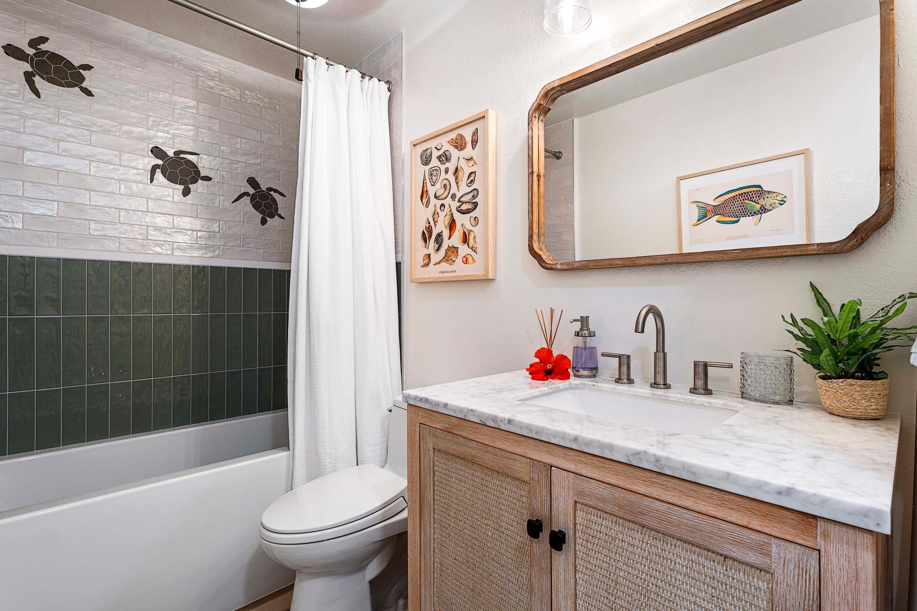 A bathroom with a white toilet, a bathtub, a shower with a white curtain, a marble sink, wooden cabinets, a mirror, and two framed pictures on the wall.