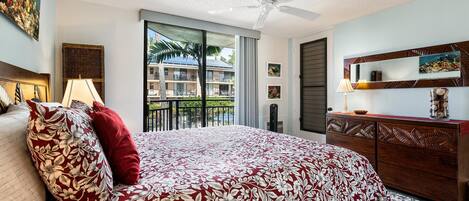 Un dormitorio con una cama grande, un ventilador de techo, un aparador y vistas al balcón exterior.
