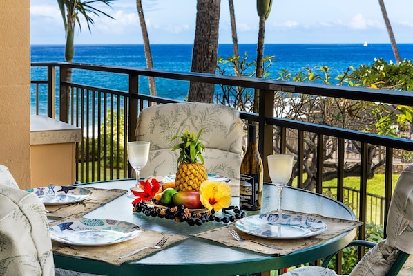 A table set with plates, a bottle, and tropical fruits, overlooking a scenic ocean view.