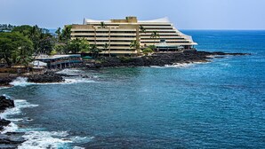A hotel with a modern architectural design, located on a rocky coastline with ocean views. - Kona Alii 608 (Kailua-Kona)