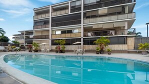 En modern, flervåningsbyggnad med en swimmingpool framför.