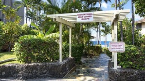 A pathway leading to a building with a sign indicating a recreational area closure at 10:00 PM. - Kona Shores#130 (Kailua-Kona)