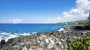 A rocky shoreline with a view of the ocean and a cruise ship in the distance. - Kona Shores#130 (Kailua-Kona)