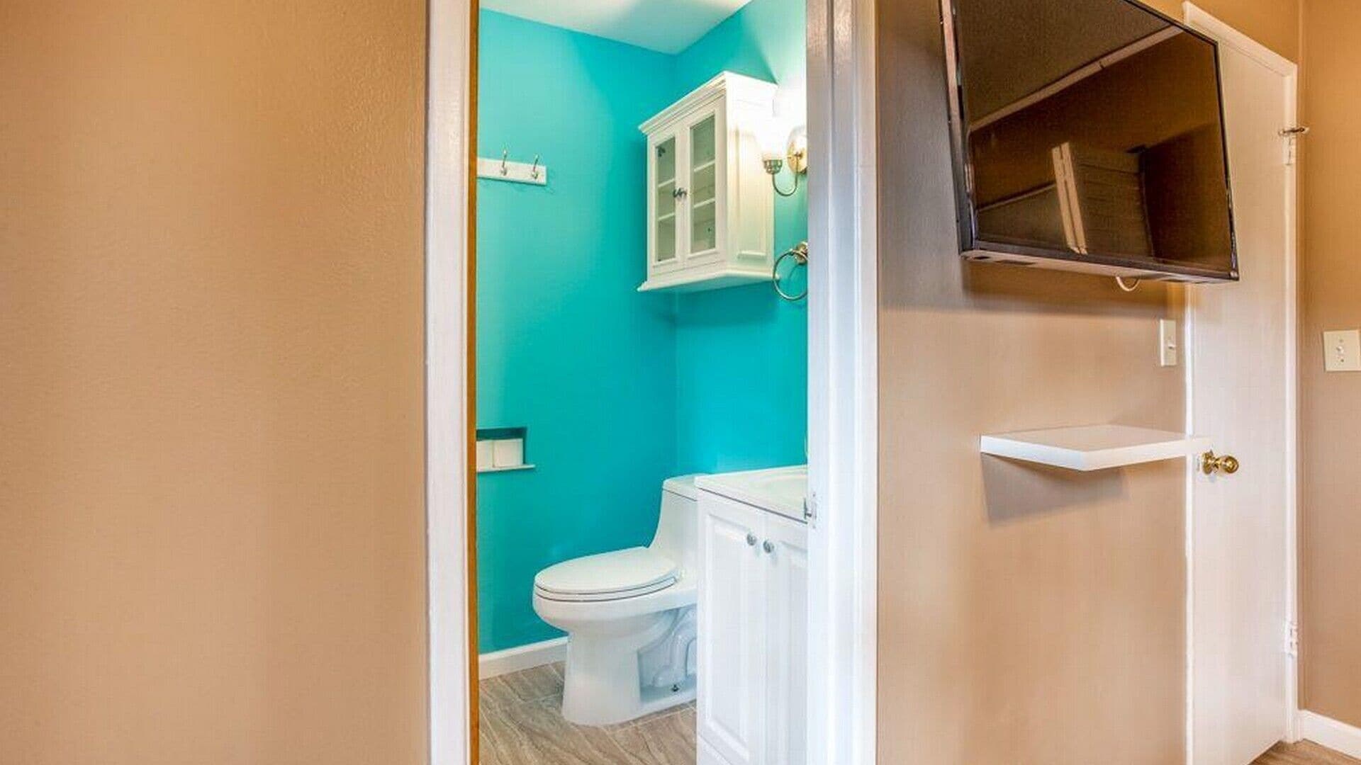A bathroom with a toilet, a cabinet, and a mirror.